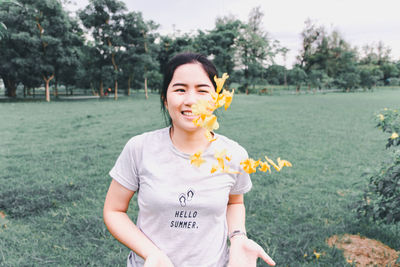 Woman throwing flowers while standing against trees