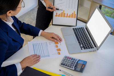 Business people discussing over graph at desk in office