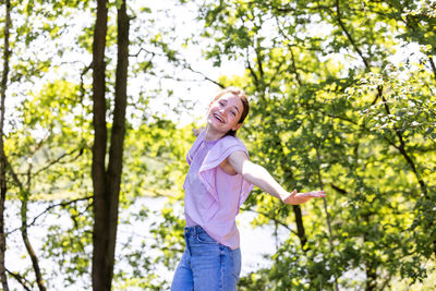 Portrait of young woman standing against trees