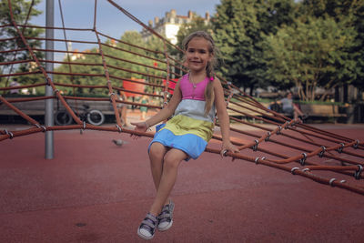 Girl sitting on rope in park