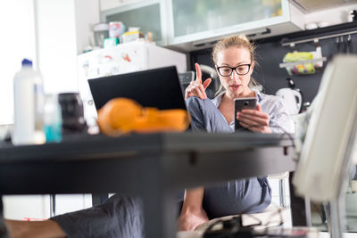 Businesswoman using smart phone sitting at home