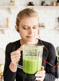 Close-up of woman listening music holding blender