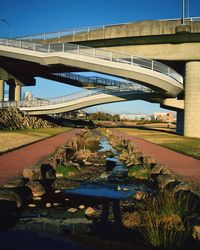 Stream amidst footpath below bridge