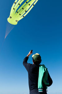 Low angle view of man standing against clear blue sky