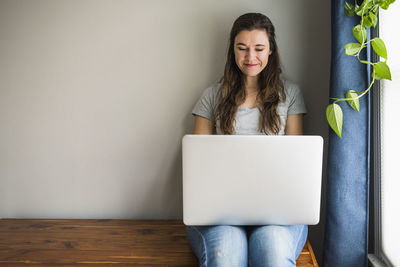 Smiling portrait of individual woman on her laptop at home