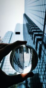 Low angle view of person holding glass building