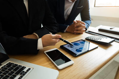 Midsection of colleagues discussing at desk in office