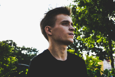 Portrait of young man looking away against sky