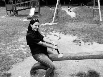 Smiling woman sitting on play equipment at park