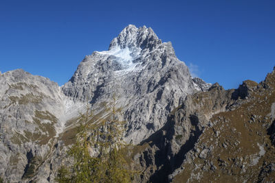 Low angle view of snowcapped mountain against clear blue sky