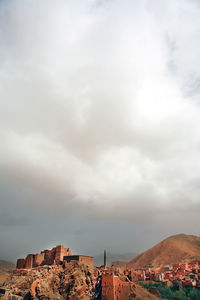 View of houses on mountain against cloudy sky