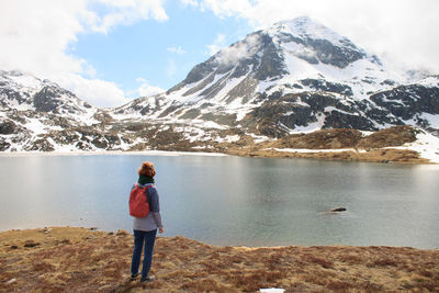 Rear view of woman standing by lake against mountain