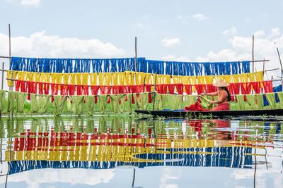 Rear view of man swimming in pool by lake against sky