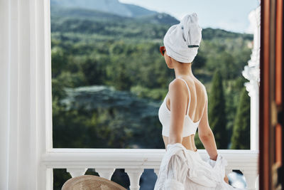 Side view of woman standing against window