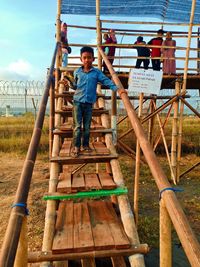 Full length portrait of man standing in ladder