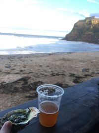 Close-up of beer on beach against sky