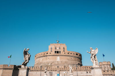 Low angle view of statue of building against blue sky