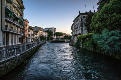 Canal amidst buildings against sky in city