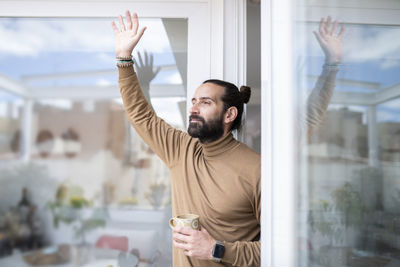 Man with arms raised in glass window