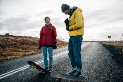 Rear view of people standing on road against sky