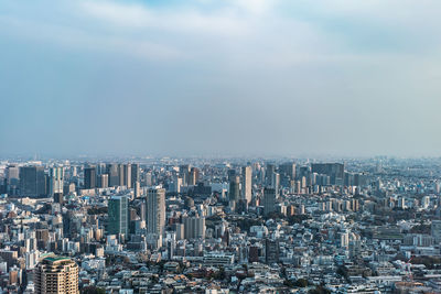 Aerial view of buildings in city against sky