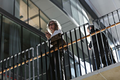 Low angle view of man standing by railing against building