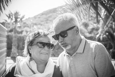 Senior couple wearing sunglasses against trees