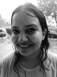 Close-up portrait of smiling wet young woman outdoors