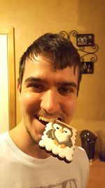 Close-up portrait of young man holding ice cream at home