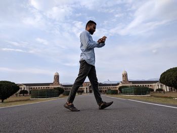 Full length of man standing on road against sky in city