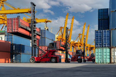 Cranes at commercial dock against sky