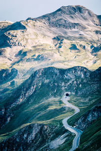 High mountain pass road through the impressive european alps with car and a tunnel seen from above