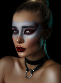 Close-up portrait of a young woman over black background