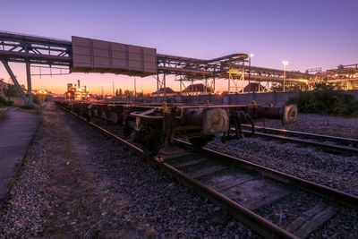 Train on railroad tracks against sky during sunset