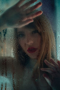 Portrait of woman seen through wet window in rainy season