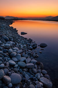 Rocks at sea shore against sky during sunset