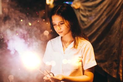 Young woman looking at illuminated camera