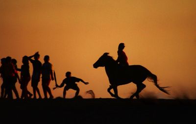 Silhouette people against sky during sunset