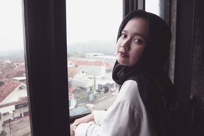 Portrait of woman looking through window