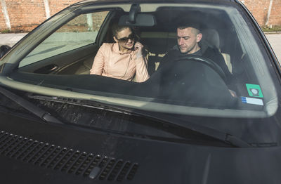 Friends sitting in car seen through windshield