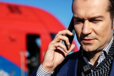Close-up of businessman communicating over mobile phone outdoors.