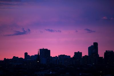 Illuminated cityscape against sky at sunset