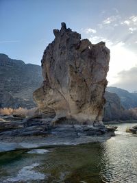 Rock formation on shore against sky