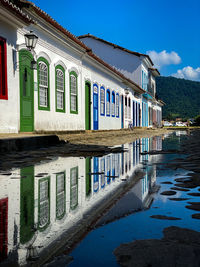 Buildings by canal against blue sky