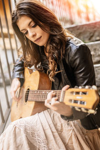 Midsection of a young woman playing guitar