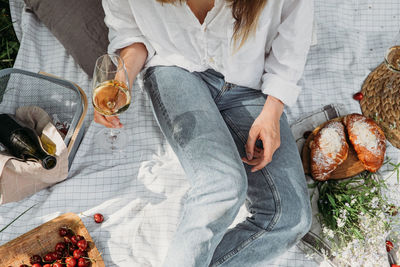 Woman in straw hat on picnic holding a glass of wine top view. aesthetic picnic outdoors with wine 