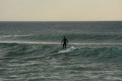 Man surfing in sea against sky