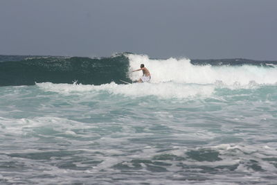 Man surfing in sea against sky