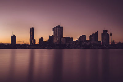 Sea by modern buildings in city against sky