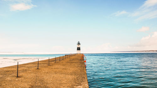 Lighthouse by sea against sky